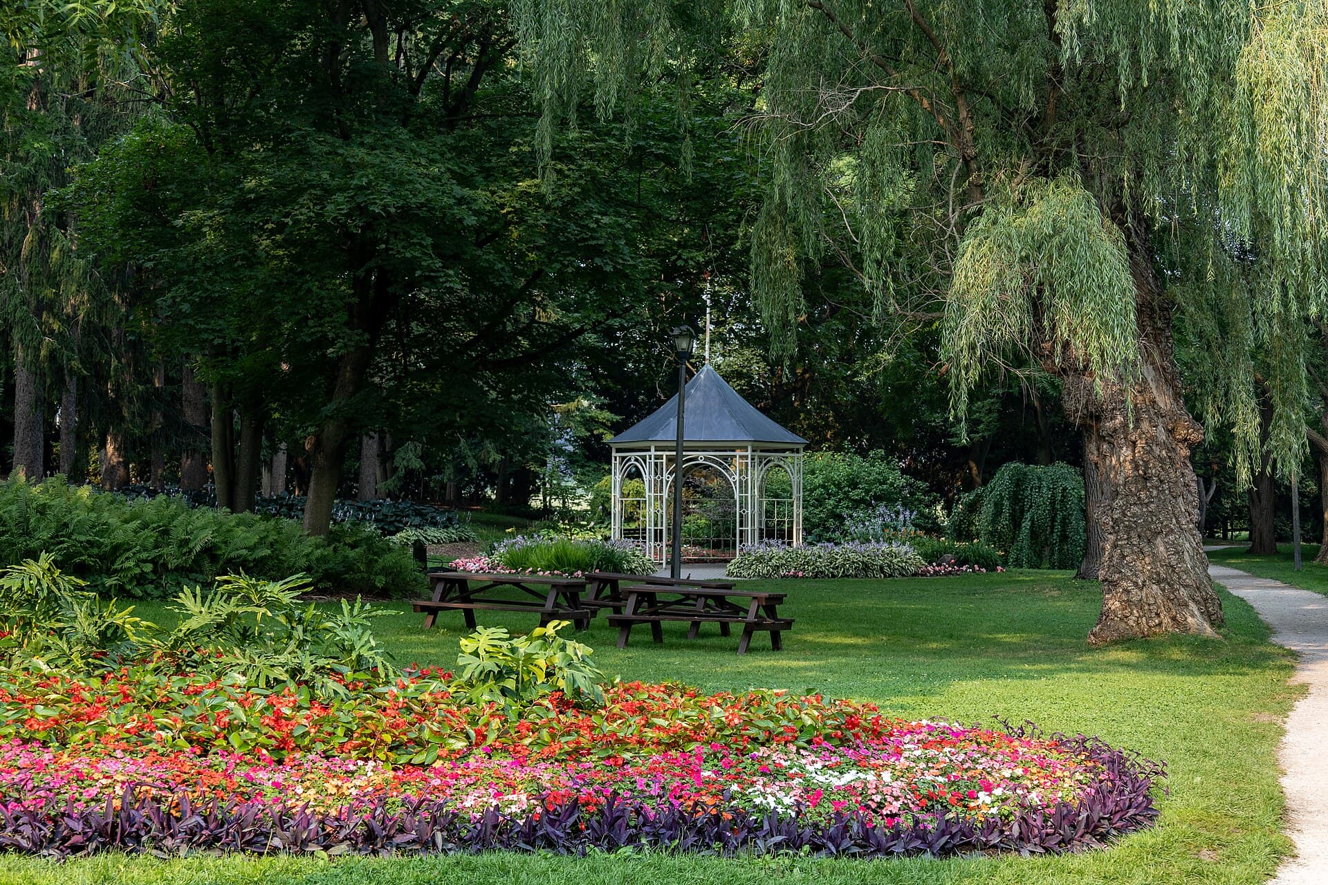 The white gazebo and flowerbeds of the Shakespearean Gardens in Stratford, framed by willows